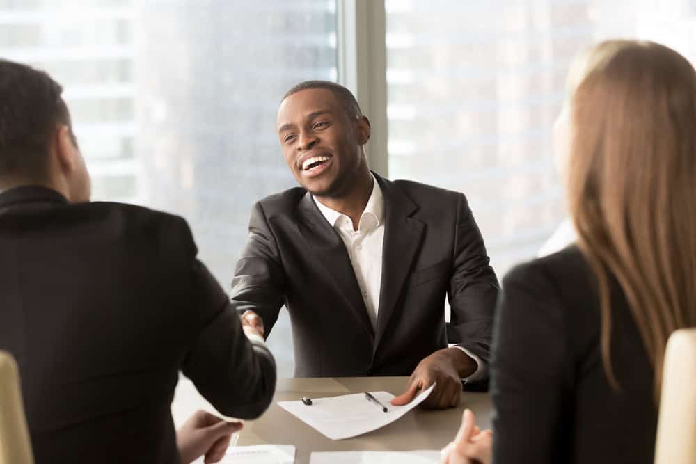 An image of an african american man smiling and shaking hands